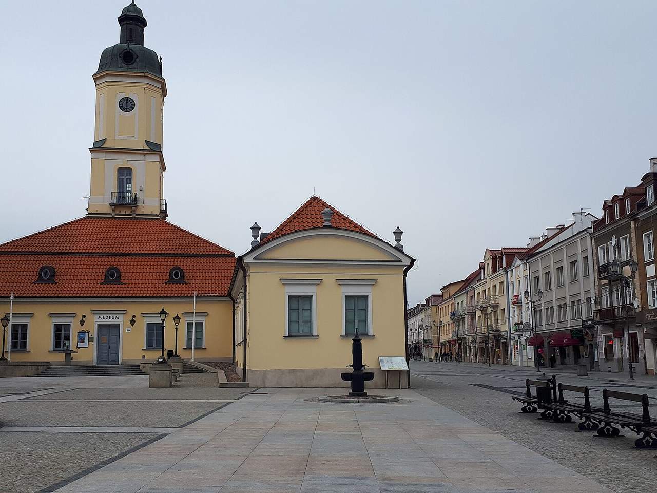 Balstogės Kosciuškos aikštė su geltonu rotušės bokštu ir raudonu čerpių stogu apsiniaukusią dieną
